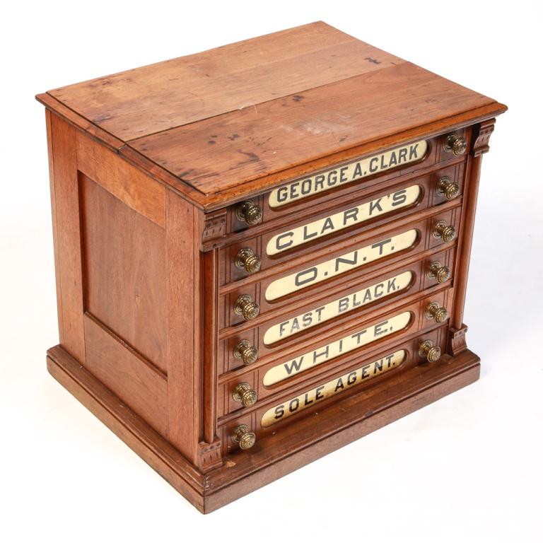 AMERICAN O.N.T. SPOOL CABINET.: Fourth quarter 19th century, walnut with pine secondary. Eastlake Victorian details, six drawers with finger joints, brass pulls and gold reverse painted labels with black lettering. 22.5"h. 24.5"w. 1