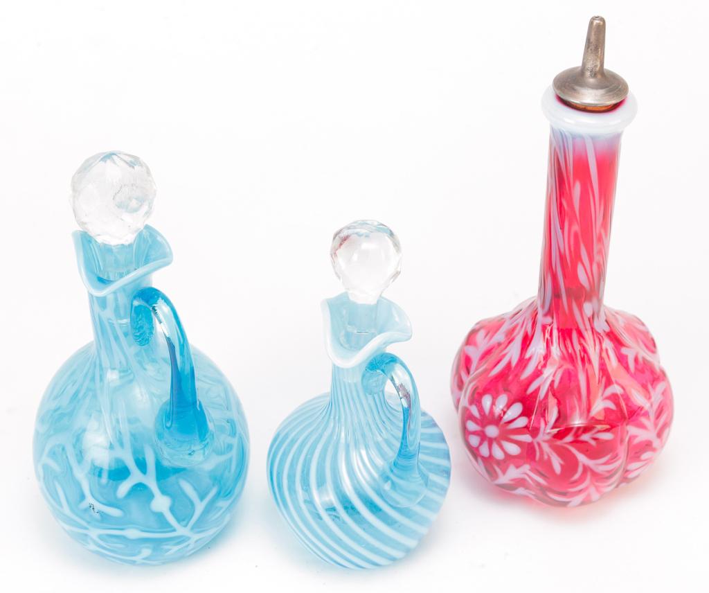 THREE PIECES OF AMERICAN OPALESCENT GLASS.: Late 19th-20th century. Two electric blue cruets. Swirled Ribbed Optic with polished pontil, 6"h. and Seaweed, 7.25"h. And a cranberry Daisy & Fern barber bottle. 7.5"h.