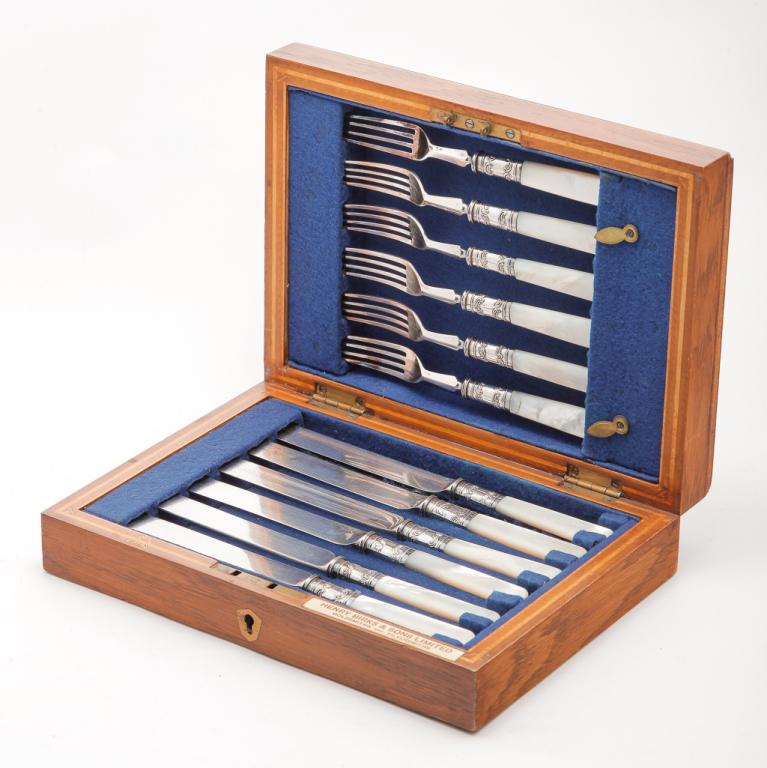 MOTHER OF PEARL HANDLED LUNCHEON SET.: Late 19th century. Six each matching forks and knives with silver plate ferules. Fitted wooden case marked for "Henry Birks & Sons Limited, Goldsmiths and Silversmiths" (Canadian jeweler). One fork ha