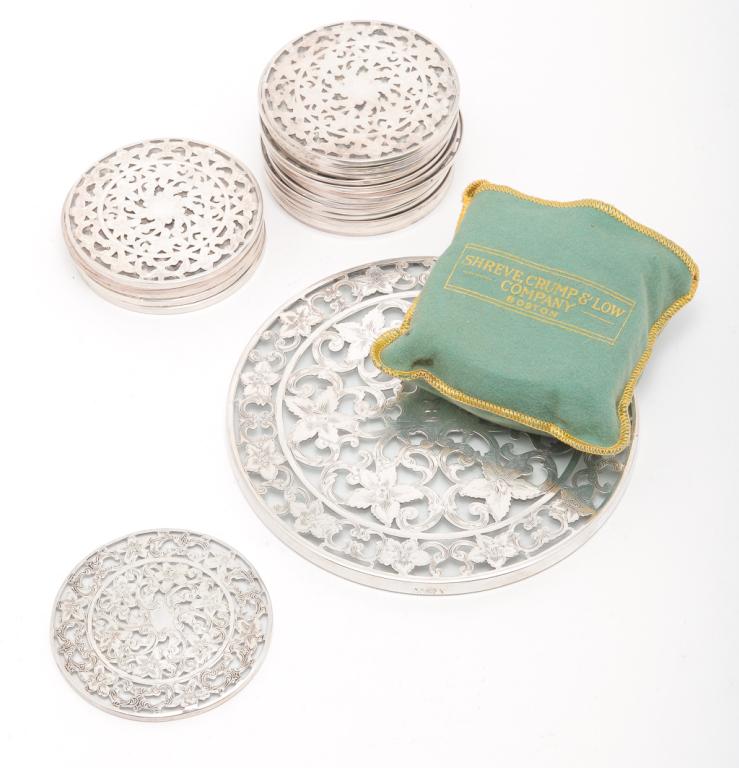 GROUP OF AMERICAN "STERLING" OVERLAY COASTERS.: Twentieth century. Glass with marked overlay. Large, 6"d. and twenty two smaller matching, 3"d. Together with ten having a matching rim design, 3"d. Some cracked glass.