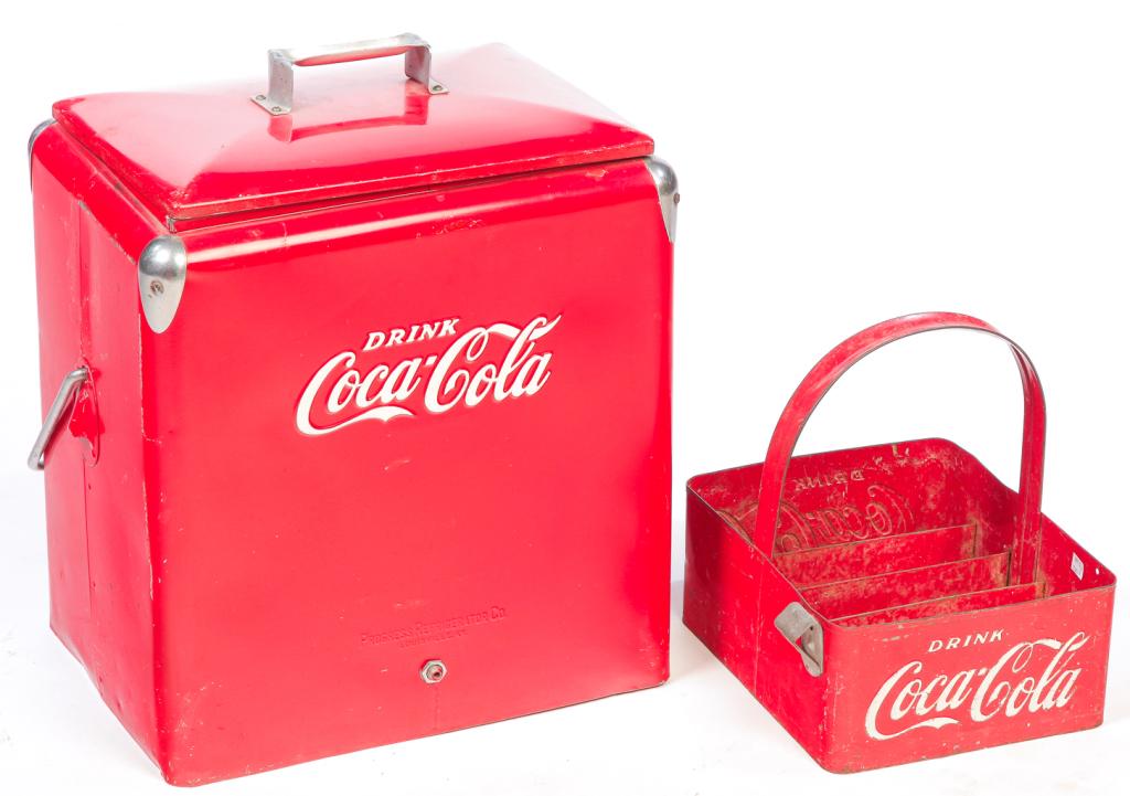 TWO AMERICAN COCA COLA PIECES.: Mid 20th century. Cooler in red and chromed hardware, embossed "Drink Coca Cola" in white. Missing chain cap. 21.5"h. 19"w. 13"d. And a bottle carrier in red with embossed "Drink Coca Cola" in white,