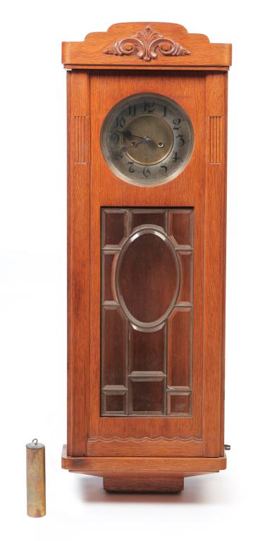 GERMAN GUSTAV BECKER WALL CLOCK.: Ca. 1890, oak. Beveled glass door, brass face, weight and pendulum. 39"h. 13"w. 5.5"d.