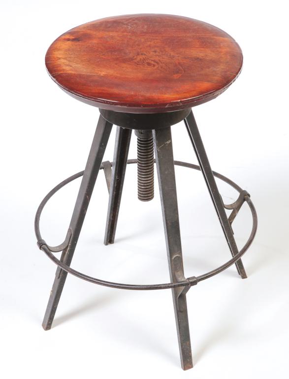 AMERICAN TROLLY CAR STOOL.: Mid 20th century. Round maple seat with carved wolf's head, tubular foot rest and cast iron threaded height adjuster. 22.5"h. 17.5"d.