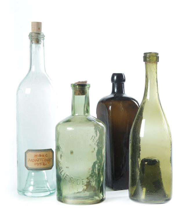 FOUR EUROPEAN GLASS BOTTLES.: Eighteenth-20th century. English amber/olive gin bottle. Bruise with blister. 10"h. and two with high kick ups. Green, tiny bubbles, 11"h. and aqua with inked label "Marc Montlouis 1952". Together wit