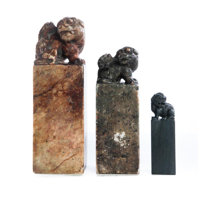 THREE CHINESE CHOP MARKS.: Early 20th century. All have foo dog finials. Two are soapstone with carved seals and text. 5.5", 6.75"h. The third is blank hardstone, 3.5"h. Minor flaking.