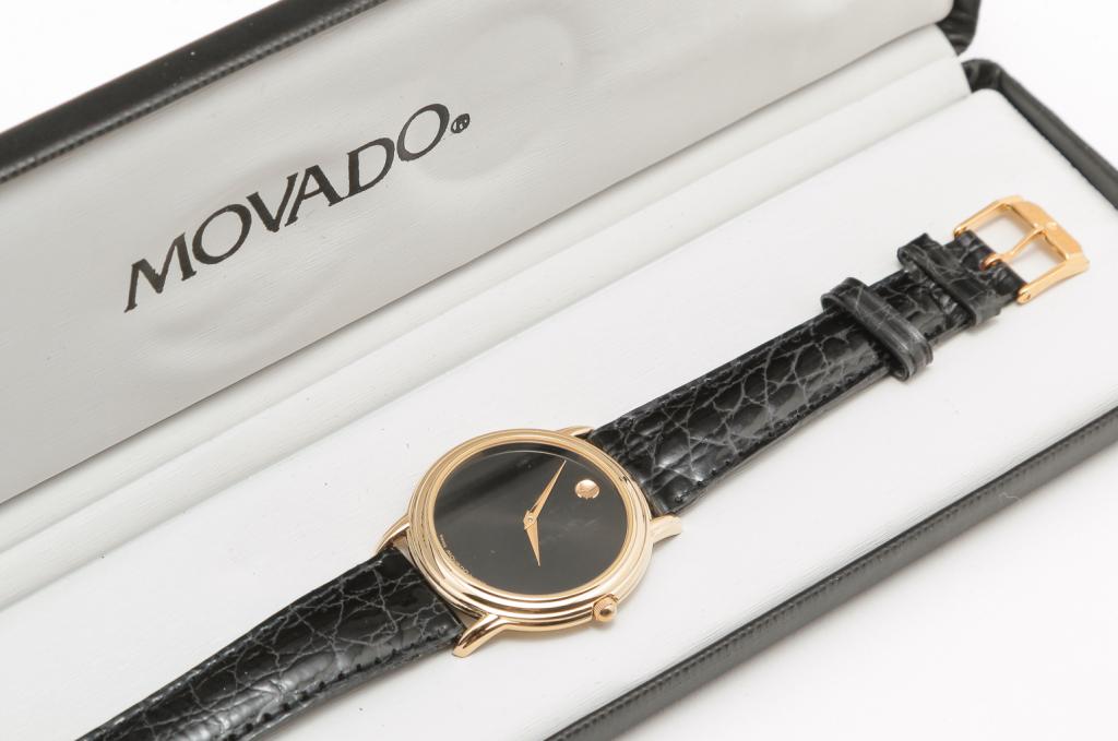 MENS MOVADO MUSEUM WATCH.: Swiss, late 20th century. Movado men's Museum Watch, 2-tone stainless/gold plated case, black dial, push/pull crown, quartz movement. Original box and manual, appears to have not been worn.