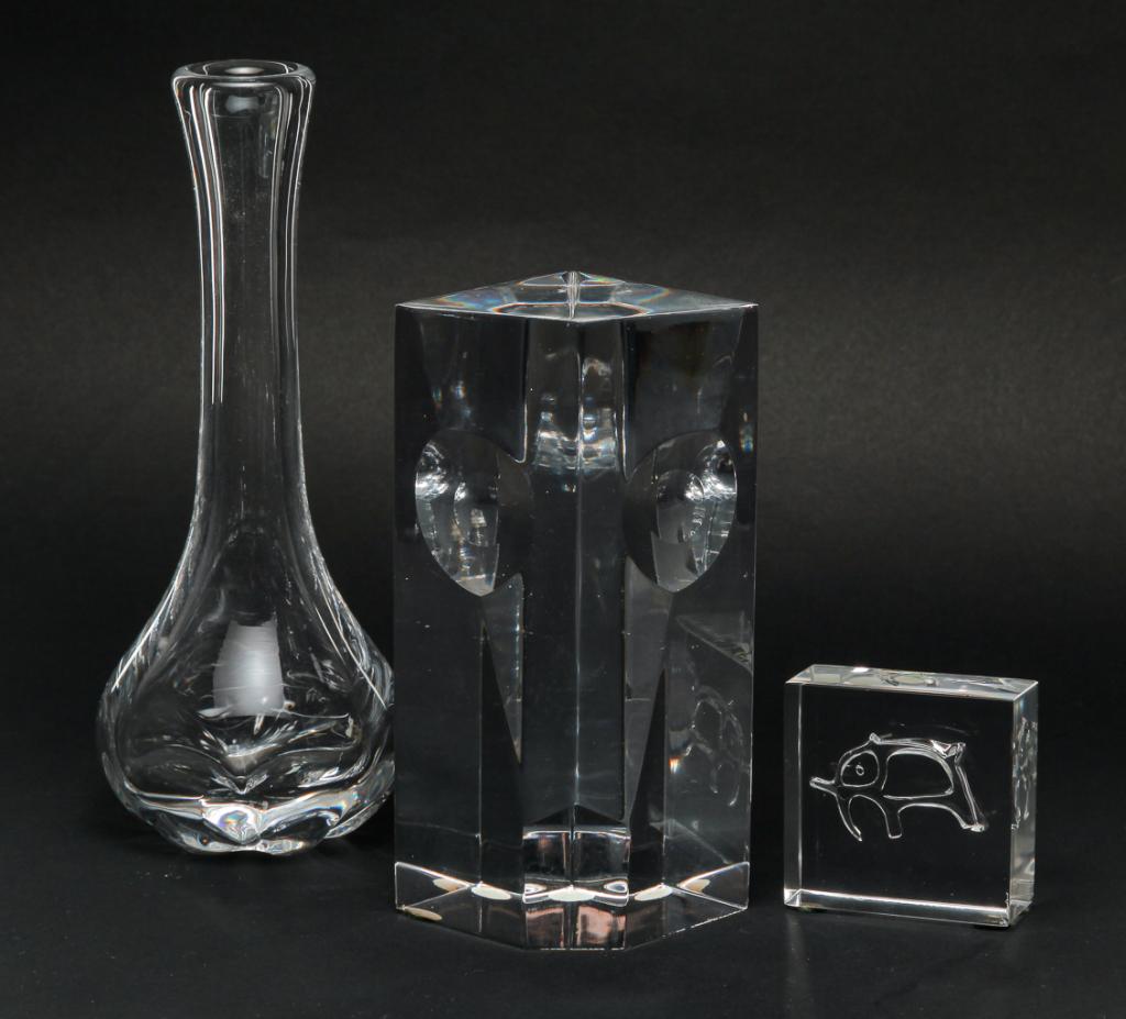THREE CLEAR SWEDISH ORREFORS PIECES.: Late 20th century. "Expo" cubist face sculpture signed "S. Palmqvist", numbered "732-71", 6.25"h. and a stick vase with ribbed base, numbered "NV 200-211", 8.25"h. Together with an elephant trapped ai