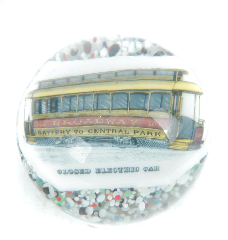 NEW YORK STREETCAR PAPERWEIGHT.: American, 4th quarter 19th century. Yellow and red streetcar "Broadway, Battery to Central Park" on side with title bellow "Closed Electric Car" on white background with splatter glass below. 3"h. 4"d