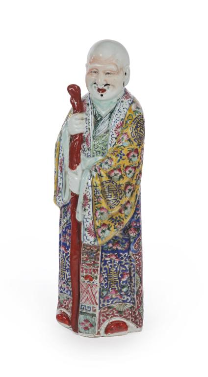 CHINESE PORCELAIN DEITY.: First half 20th century. Standing figure of the God of Longevity with a staff and colorfully glazed robes. Holes for beard and moustache. Impressed mark on the underside. Flaking and some repair at st