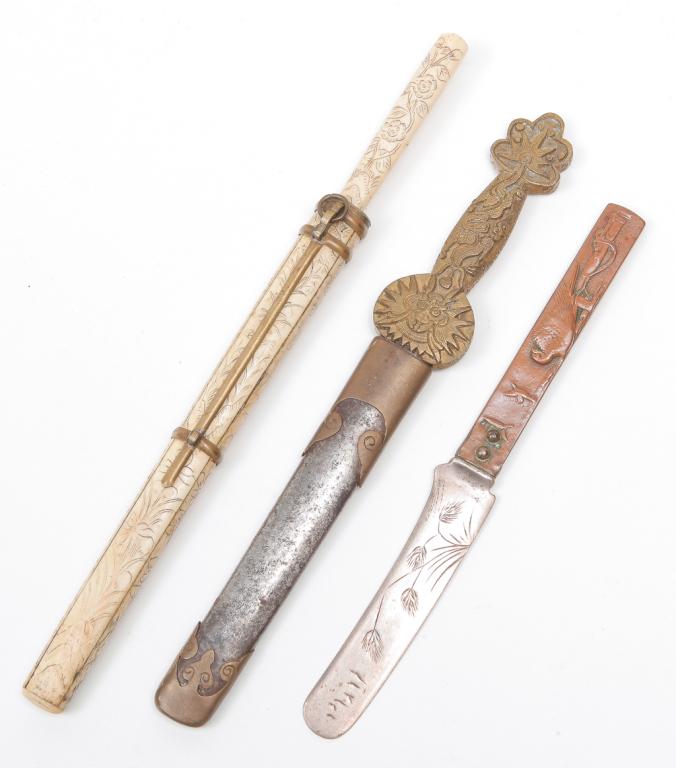 TWO KNIVES AND A LETTER OPENER.: Twentieth century. Japanese knife with incised bone handle and scabbard. Similar to traveling utensil sets. 9.75"l. and a letter opener in the form of a Chinese sword with brass dragon handle, 9"l. To