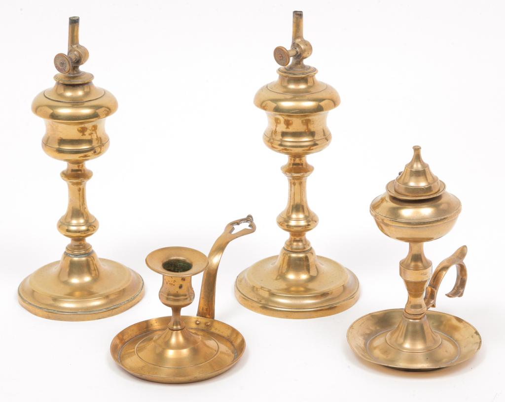FOUR EUROPEAN BRASS LIGHTING DEVICES.: Nineteenth century. Pair of camphene lamps marked "Gadron" on the wick knobs, 9.25"h. and whale oil chamber lamp with lid. Replaced wire hinge. 6.75"h. Together with a chamberstick, 3"h. Some minor de