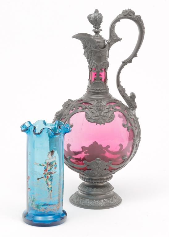 TWO PIECES OF EUROPEAN GLASS.: Late 19th century. Cranberry ewer with Baroque style openwork pewter frame and stopper, 13.25"h. And an electric blue cylinder vase with ruffled top and enameled jester decoration. 6.25"h.