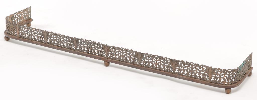 EUROPEAN BRASS FIREPLACE FENDER.: Late 19th century. Cast foliage and scrollwork, cast iron bottom rail and spherical feet. 4.75"h. 50"w. 11"d.