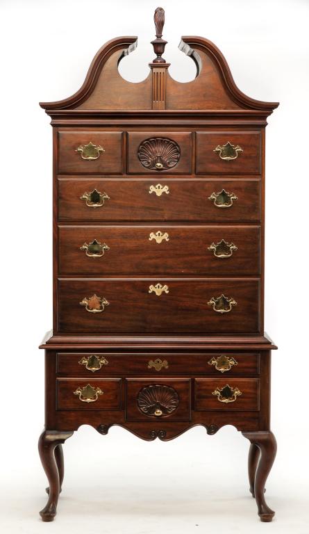 HENKEL-HARRIS QUEEN ANNE STYLE HIGH CHEST.: Second half 20th century, mahogany with oak secondary, two pieces. Virginia Galleries: Philadelphia style, bonnet top with urn and flame finial, top row of three drawers, center with shell carving, ov