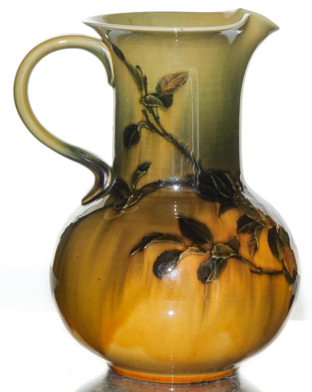 ROOKWOOD STAND GLAZE PITCHER BY MATT DALY.: Dated 1889. No shape number. Seed pods decoration. Signed on bottom. Minor wear on table ring. 8.75"h.