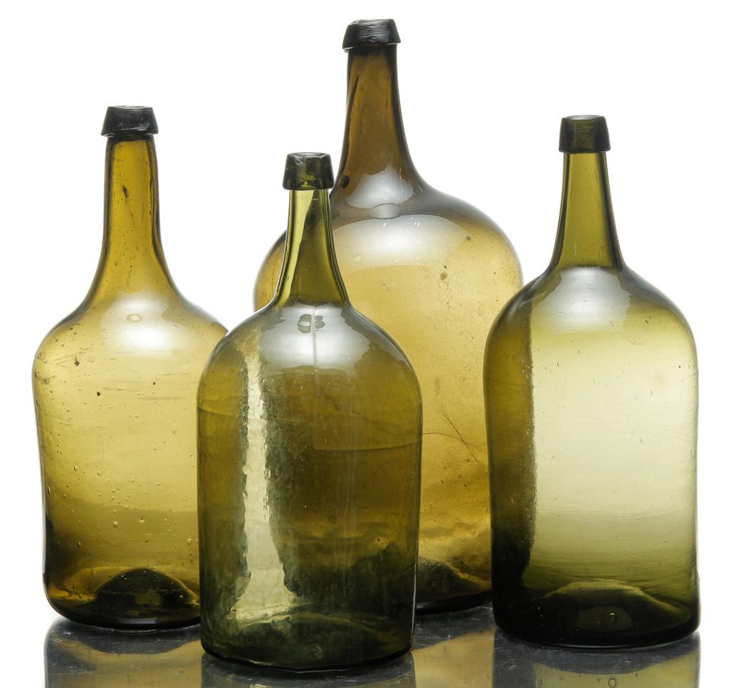 FOUR EUROPEAN DEMIJOHNS.: Mid 19th century. All in olive green with blob tops. Largest has broken pontil, 17.75"h., middle two have iron pontils, 15.5", 15"h. and smallest is blown from the top down, 14.5"h.