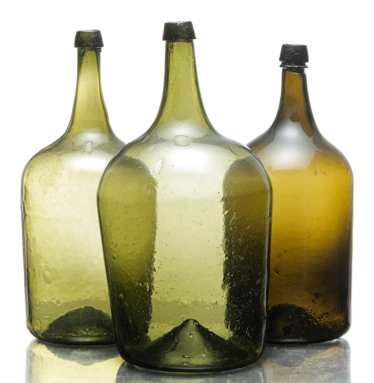 THREE EUROPEAN DEMIJOHNS.: Mid 19th century. Olive green with straight sides and blob tops. Largest have broken pontils, 19", 18.5"h., smallest is blown from top down, 14.5"h.