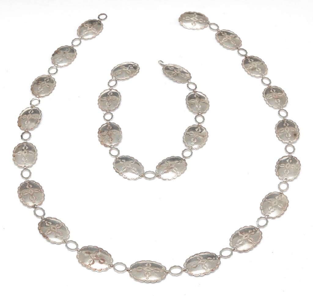 NATIVE AMERICAN SILVER CONCHO BELT & NECKLACE.: 2nd half - 20th century. Sterling silver (tested) concho belt approx. 33"l, comprised of eighteen oval conchos with stamped design, hook and eye closure. Necklace measures approx. 14.5"l, comprised of