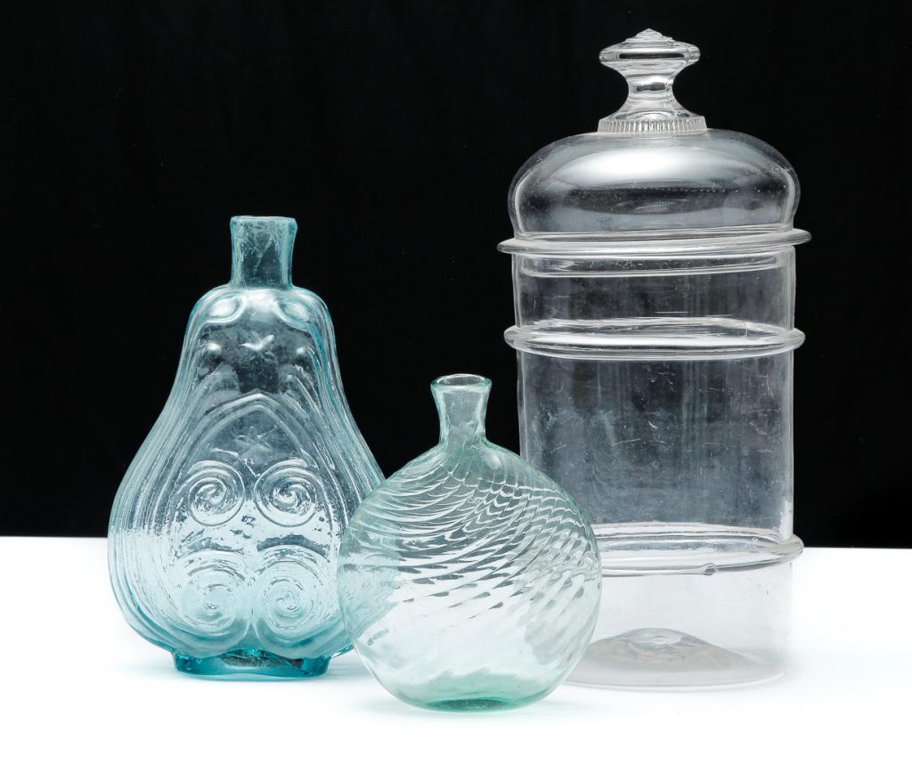 THREE PIECES OF AMERICAN GLASS.: First half 19th century. Swirled aqua flask with broken pontil, 6"h., aqua scroll flask with iron pontil, 8.75"h. and a clear, probably Pittsburgh, canister jar with blown two ring base and pressed li