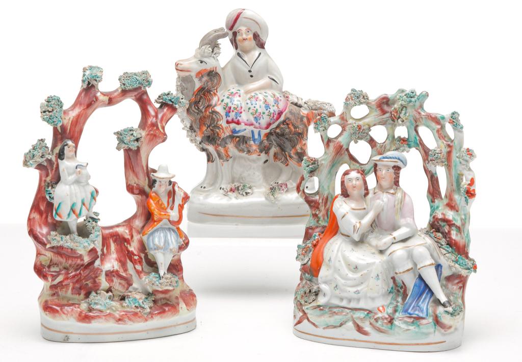 THREE ENGLISH STAFFORDSHIRE FIGURINES.: Third quarter 19th century. Young lady riding a colorful goat, 5.75"H., courting couple under a trellis of vines, 6"h. and a man and woman, she with a pitcher and he with a stringed instrument, standi
