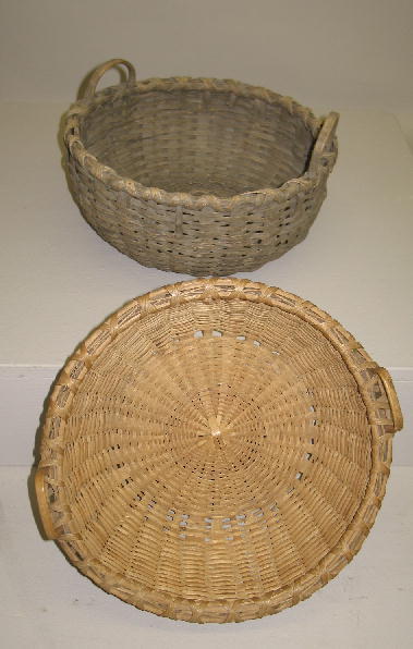 TWO WOVEN SPLINT BASKETS. Both are round and have: TWO WOVEN SPLINT BASKETS. Both are round and have raised double handles. One has late grey paint. 12 1/2"d. 6 1/2"h. The other has a natural tan color. Broken splints along the lower edge. 12 1/2"d. 5