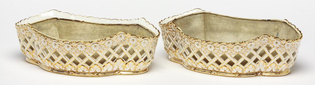 A PAIR OF ENGLISH MINTON CHINA PLANTERS.: First quarter 20th century. White bone china with basket weave reticulation and gold trim. Shaped tin liners and "John Mortlock" retailers mark. 3.5"h 19"w 7.5''d