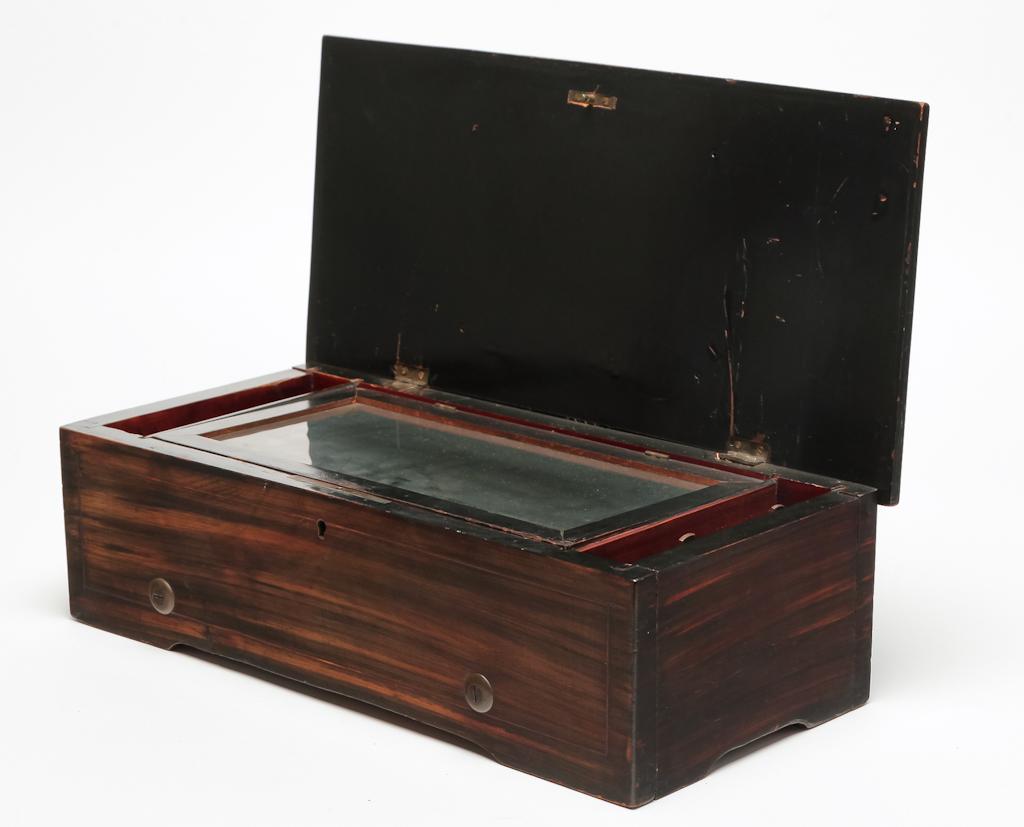 SWISS CYLINDER MUSIC BOX.: Late 19th century. Mahogany lid with line and floral inlay and case with rose woodgrain painting. Brass lever wind movement and eight tune cylinder. 5"h. 16.5"w. 8"d.