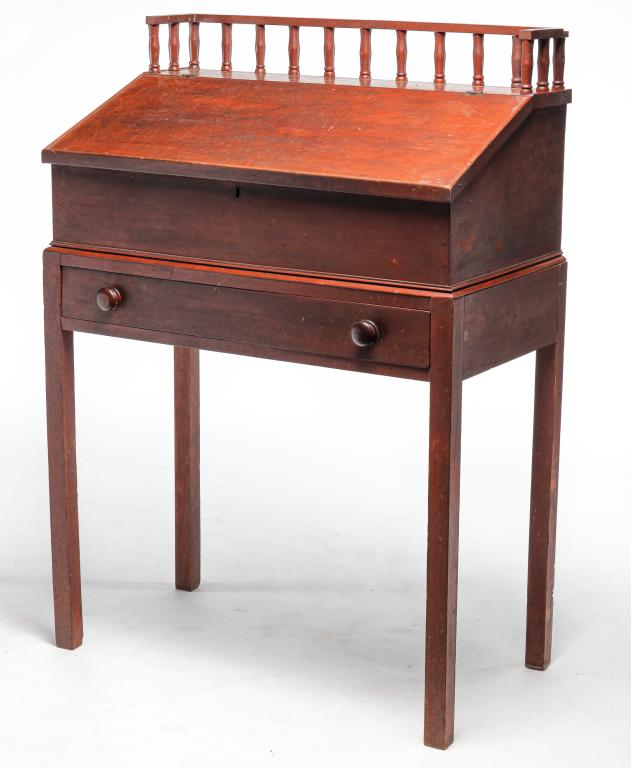 AMERICAN CLERK'S DESK.: Mid 19th century, poplar. One piece with dovetailed case. Slant lift lid, gallery top with turned posts, dovetailed drawer and fitted interior with multiple dovetailed drawer. Original red stain. Mino