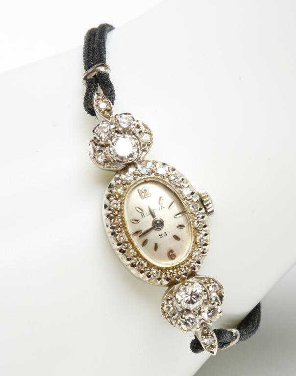 VINTAGE LADIES 14K DIAMOND BULOVA WRISTWATCH.: American, mid-20th century. 14K white gold oval Bulova wristwatch with diamond bezel. Total of thirty round diamonds - eighteen around face, six accenting each lug. Total diamond weight approx. 1.16ct