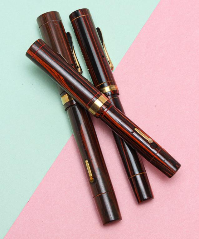 THREE WOOD GRAIN CONKLIN FOUNTAIN PENS.: Circa 1925. Three Conklin Endura hard rubber wood grain fountain pens, all lever fill and stamped on lever 'PAT.NOV.17.1925' with embossed crescent. One oversize pen,5.25"l, some wear to gold filled t