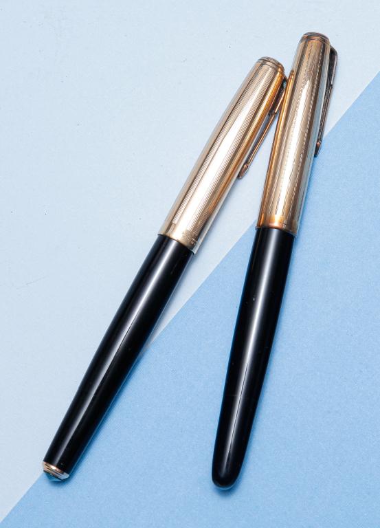 TWO VINTAGE PARKER 51 VACUMATIC FOUNTAIN PENS.: American, mid-20th century. Both pens with black barrels, 1/10 - 14K gold filled caps, vacumatic plunger filling. Some discoloration to caps, surface wear. Plungers appear to be in working condition b