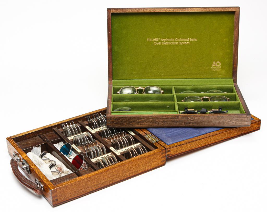 TWO BOXES OF OPTOMETRISTS' LENSES.: Twentieth century. One in oak case with multiple lens samples "M. Wiseman and Co. London." 2.5"h. 10.25"w. 11"d. And "American Optical" cataract lens, 2.25"h. 13.25"w. 8"d.