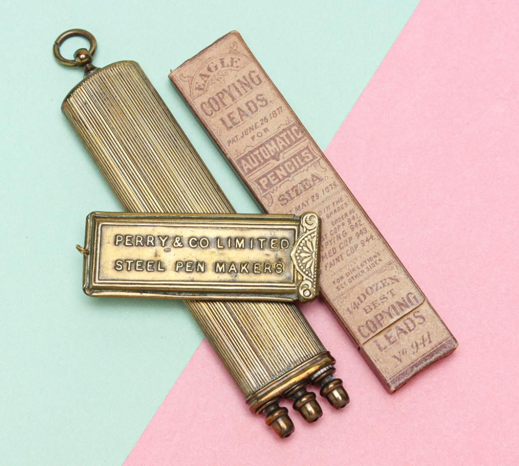 TWO VINTAGE BRASS WRITING ACCESSORIES AND LEAD.: Late 19th century. Includes: unusual ribbed flat tubular case with three round slots, each for one cylindrical shaped, retractable propelling tool - dip pen, pencil, and knife, each with small colored