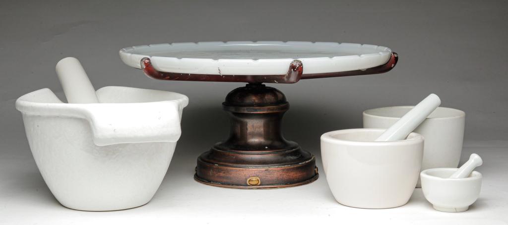 FIVE AMERICAN DRUGSTORE ITEMS.: Twentieth century. A revolving instruments stand with milk glass tray and brass, copper and cast white metal base, 6.75"h. 14"d. Three mortar and pestles, from 6.25" to 2.5"h. And an ironstone bowl, 3