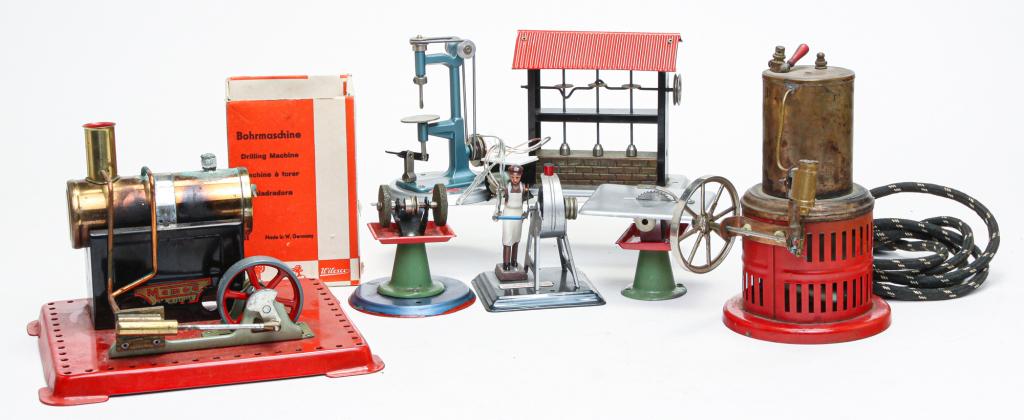 SEVEN STEAM TOYS.: Twentieth century. A Mamod boiler and flywheel, missing fuel tray, 5.75"h. 8.75"w. 7.25"d. Weeden upright boiler with fly wheel, 7"h. And five belt-driven machine tools: hammering press, drill press b