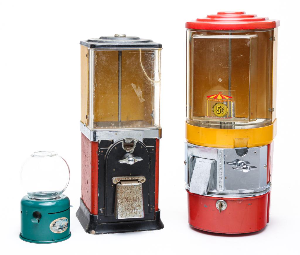 THREE GUM BALL VENDING MACHINES.: Second half 20th century. A "Junior Venda Bank," 7"h. A Carousel Industries "Vendoroma," 18"h. And an unmarked machine with crack in clear plastic front, 16"h.