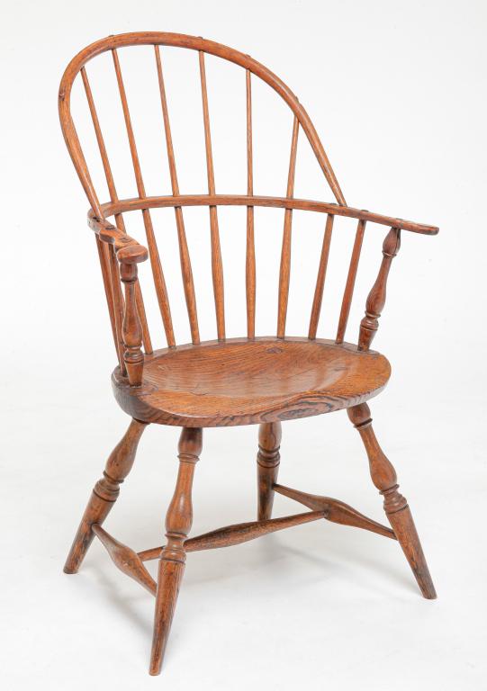 AMERICAN SACKBACK WINDSOR ARMCHAIR.: Early 19th century, ash. Turned posts, legs and "H" stretcher, and shaped arms. Age splits, removed metal rod arm supports, repairs and metal braces under the seat. 16.75" seat, 38.25"h.