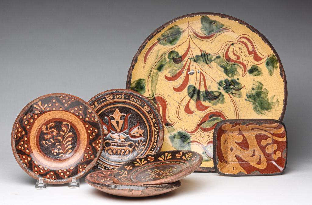 SIX PIECES OF TURTLECREEK REDWARE.: Fourth quarter 20th century. A chop plate with tulips dated 4-13-85, 12"d. Four small plates with different decorations, dated 1985, 6.5"d. And a rectangular dish, dated 1985, 5.5"w. 4.25"d.