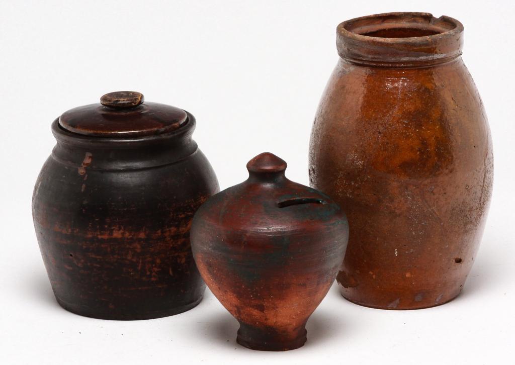 THREE PIECES OF AMERICAN REDWARE.: Nineteenth century. Jar (chip), 8"h., bank with blue paint, 5.75"h. and jar with mismatched lid (flake), 6.25"h.