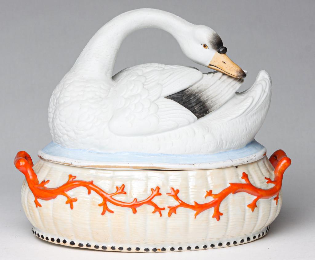 EUROPEAN BISQUE FIGURAL SWAN on NEST FORM EGG CADDY.: Second half 19th century. Swan lid, glazed nest-shaped base with orange vine or coral design and handles enclosing a glazed insert with four egg cups, 7.5"h.