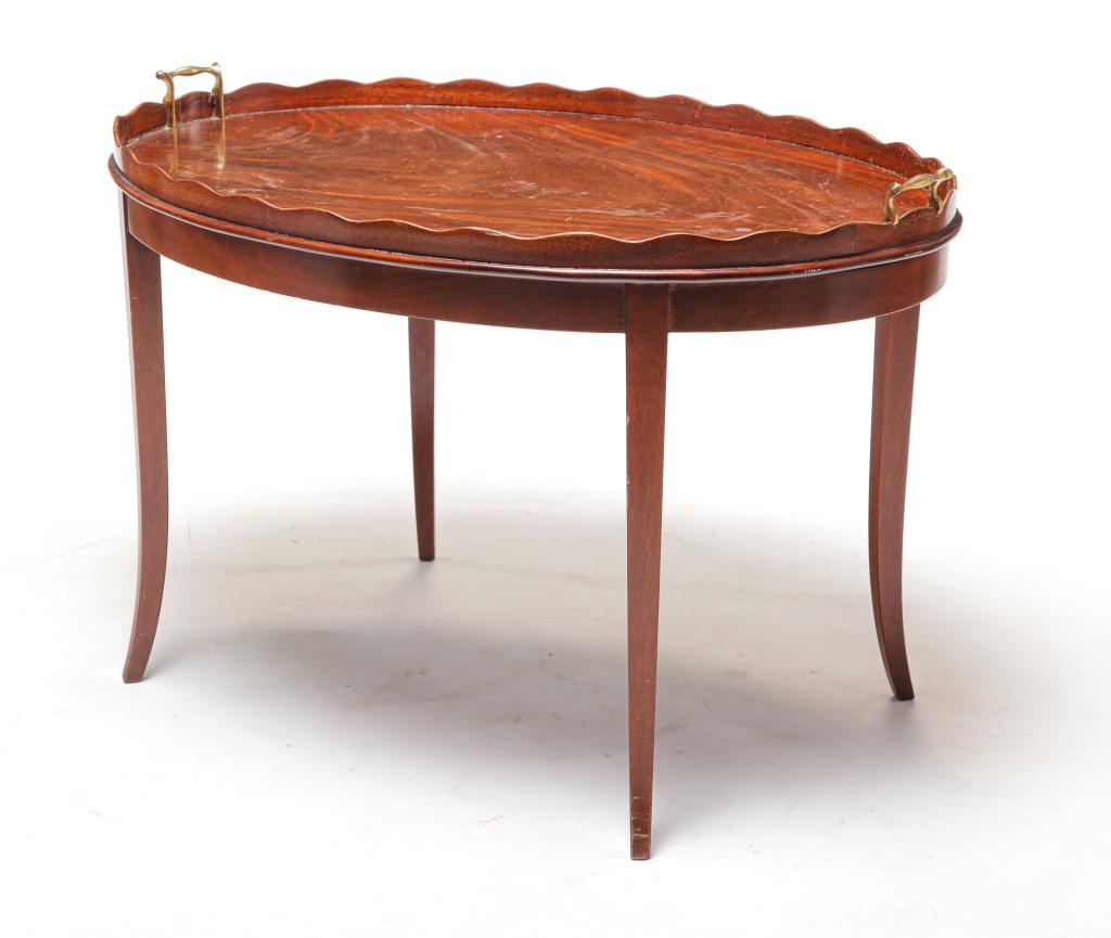 AMERICAN COFFEE TABLE.: Mid 20th century, mahogany. Constructed to a resemble a tray on stand. Scalloped gallery edge, brass handles and base with curved, tapered legs. 21"h. 31.5"w. 23"d.