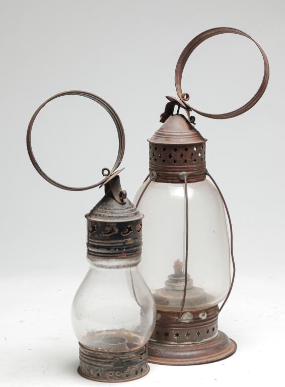 TWO AMERICAN LANTERNS.: Mid 19th century. Tin lanterns with ring handles, punched bases and glass globes. Whale oil font and wire guards. Wear, rust and added solder. 17"h. and a candle lantern with traces of old blue paint.