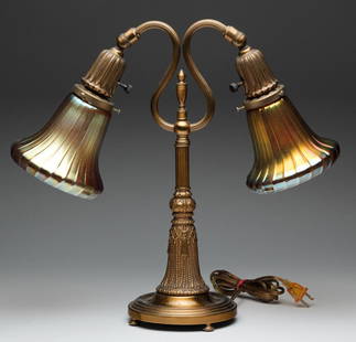 AMERICAN DESK LAMP WITH ART GLASS SHADES.: First quarter 20th century, brass base with lotus-shaped sockets, tassel -shaped stem and dish-shaped feet. Unsigned gold ribbed shades, probably Steuben. 16.5'h.