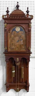 AMERICAN SETH THOMAS WALL CLOCK.: Ca. 1900, mahogany. Ornate case with turnings and pressed and cast brass ormolu, brass works with phases of the moon dial, double weights and worn painted face. 60"h. 19.25"w. 7.5"d.