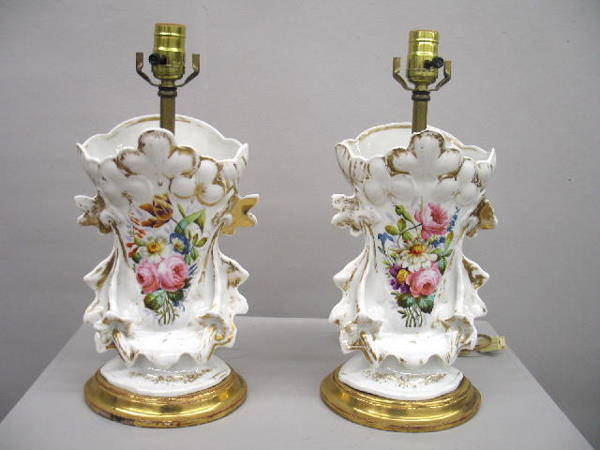 PAIR OF HAND PAINTED PORCELAIN LAMPS. White porcel: PAIR OF HAND PAINTED PORCELAIN LAMPS. White porcelain with detailed floral decoration on both sides. Gilded wood bases. Wear and one has a shallow rim chip with hairline. 27 1/2"h. with brass harps.