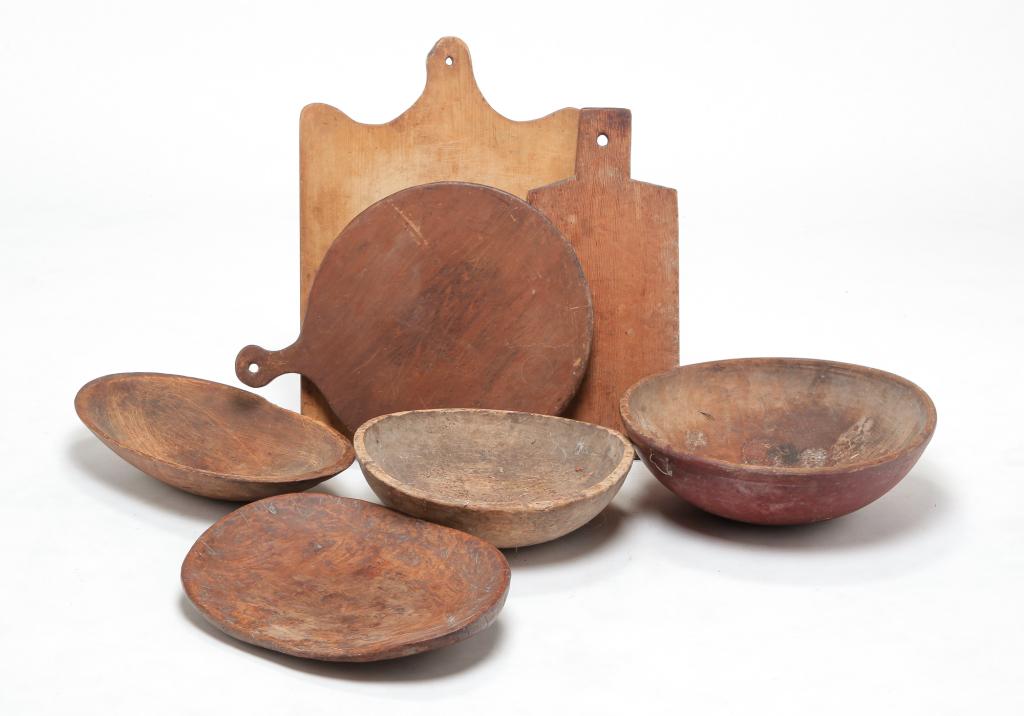SEVEN PIECES OF AMERICAN KITCHEN WOODENWARE.: Nineteenth century. Three cutting and bread boards. 26" - 22" h. Two turned bowls. 19" w. 16" w. Two trenchers. 19" w. 21" w. Splits, wear and loss.