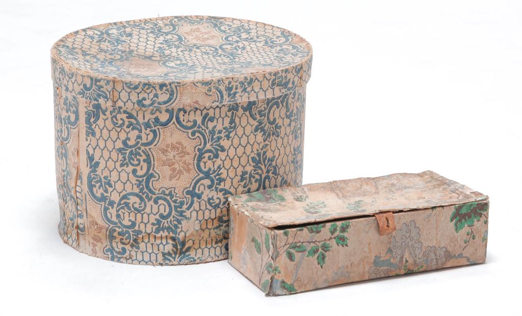 TWO AMERICAN WALLPAPER BOXES.: Mid 19th century. Oval box with blue and white floral and leaf bracket paper covering and newspaper lining, dated 1849. Water and edge damage with wear. 9.25"h. 13"w. 11"d. Rectangular box with floral