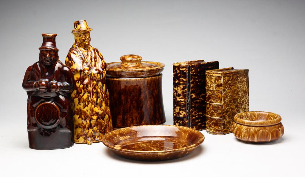 SEVEN PIECES ROCKINGHAM AND BENNINGTON.: England, America. Second half 19th century. Two Bennington book flasks with mottled glaze. Loss and professional repairs. 6.5"h. 5.5"h. Rockingham lidded jar, plate, soap dish and two coachmen flasks.