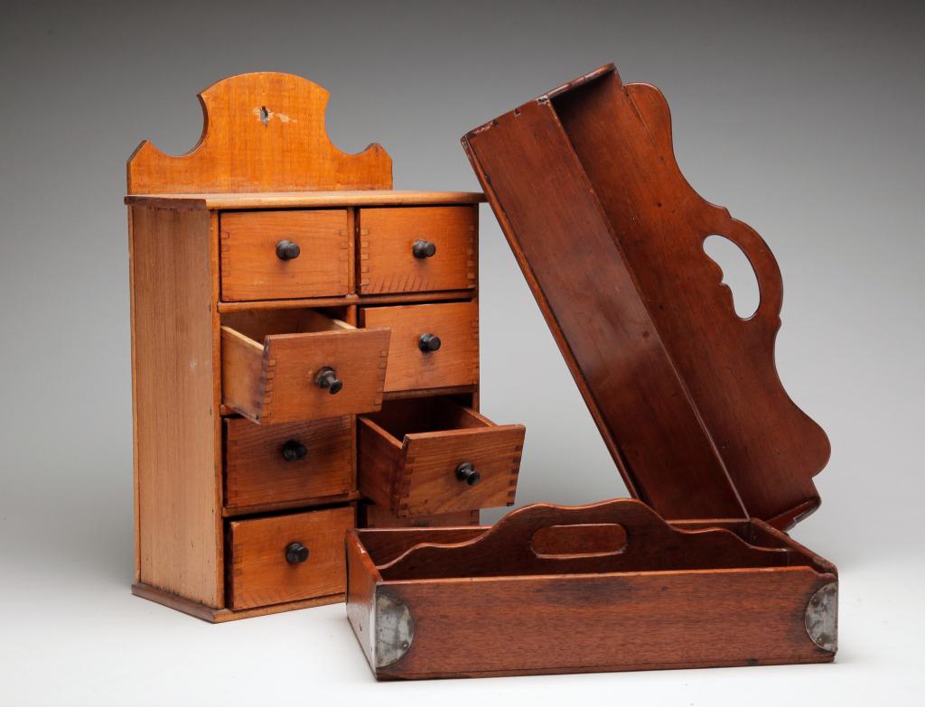 AMERICAN CUTLERY TRAYS AND HANGING SPICE CABINET.: Second half-19th century. Pine hanging spice cabinet with eight dovetailed drawers. 16.5"h. 10.5"w. Two mahogany cutlery trays. One with heart handle and canted sides. 7.25". 16"w. 8"d. One with strai