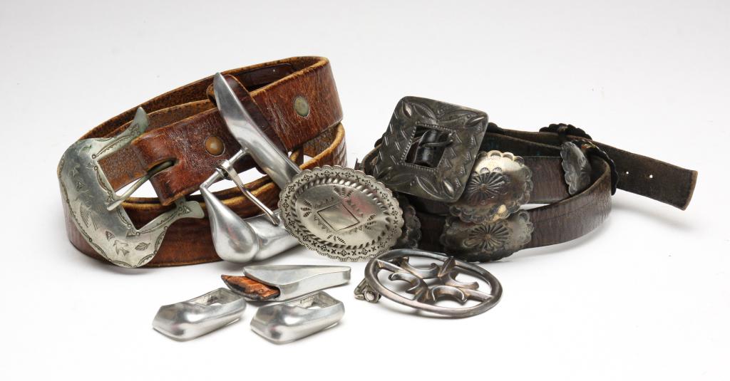 TWO VINTAGE LEATHER BELTS AND BUCKLES.: American, 2nd half - 20th century. One dark brown belt, worn, approx. 31.5"l x .75"w, eleven conchos with stamped design, rectangular buckle. One dark tan belt, worn, approx. 36"l x 1.25"w, southweste